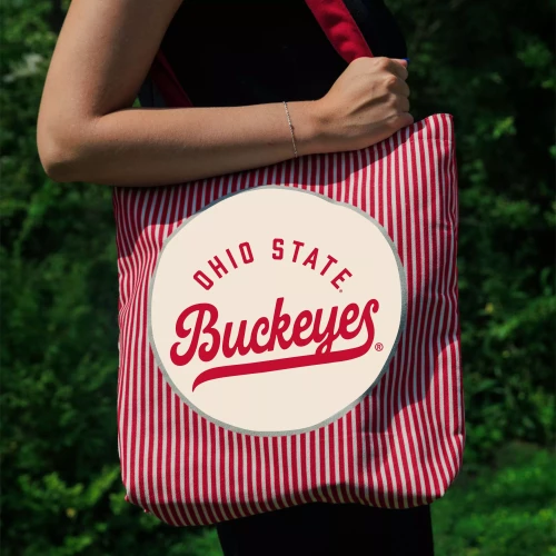 one model wears a tote on her shoulder. it is striped right and white with a circular ohio state buckeyes logo in the center