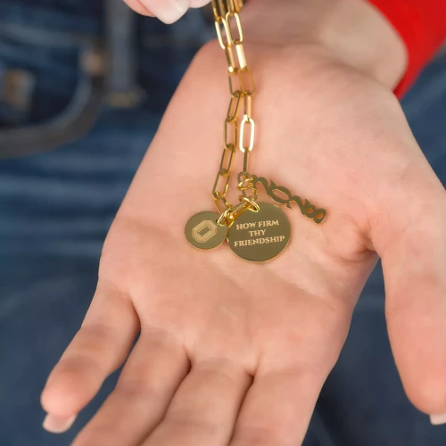 a model holds a gold bracelet with ohio state charms in her hand 