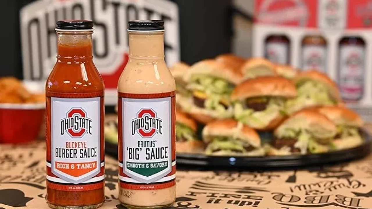 2 Signature Sauces brand sauce bottles sit in front of a platter of sliders. 
