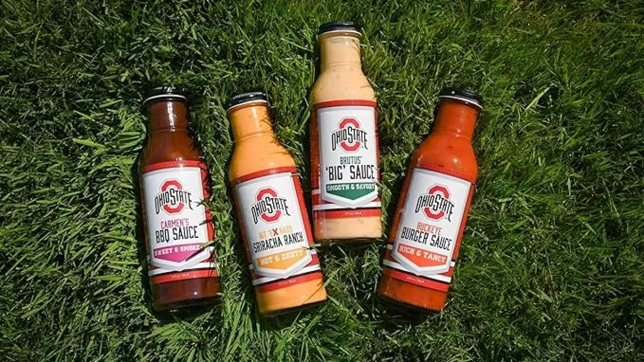 4 Signature Sauces brand sauce bottles lay in the turf. 